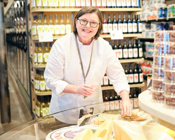 Kim Martin smiling by cheese department in store